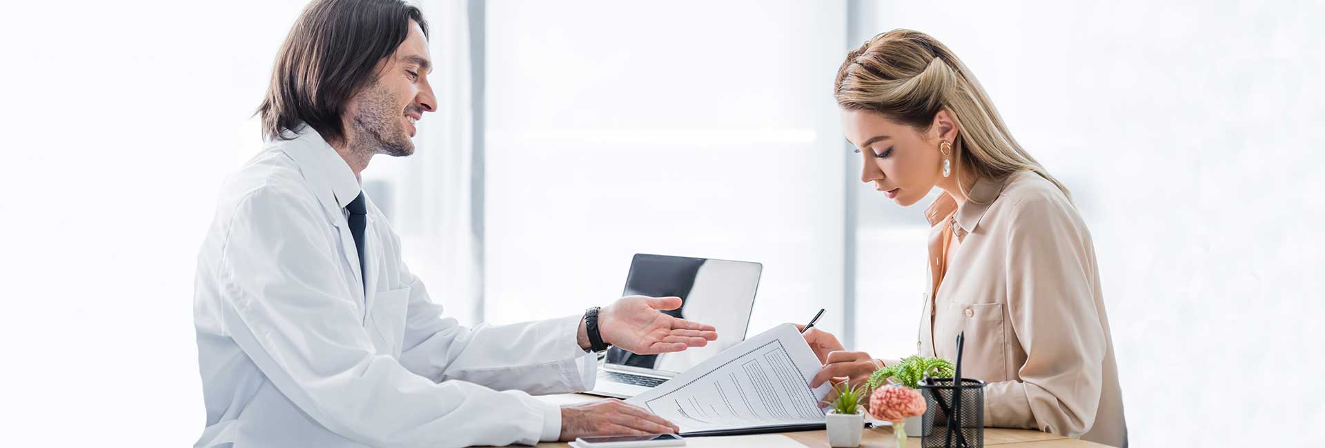 Woman signing insurance claim form during appointment